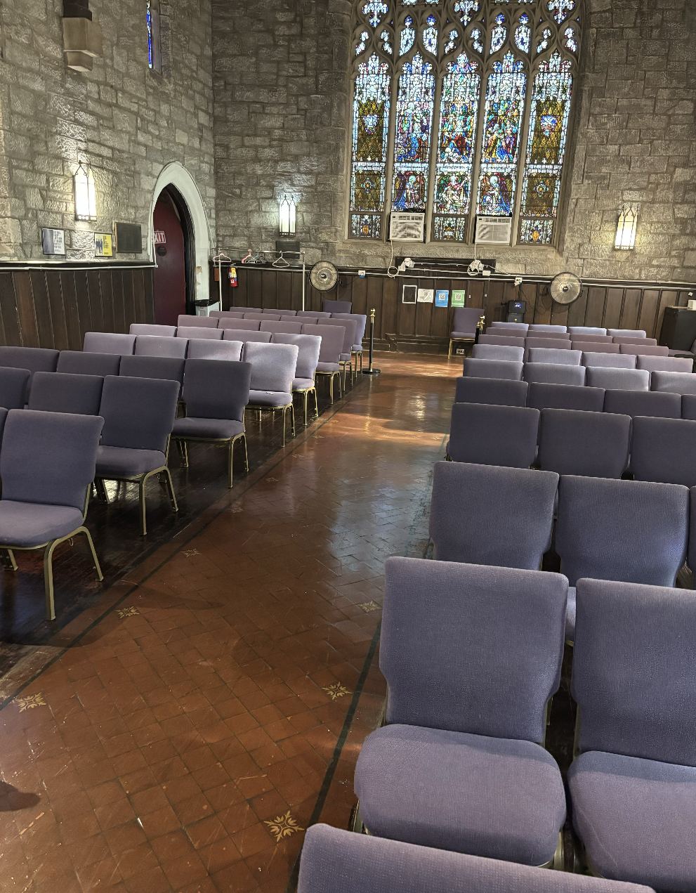 Church sanctuary with clean floors and rows of chairs under stained glass windows