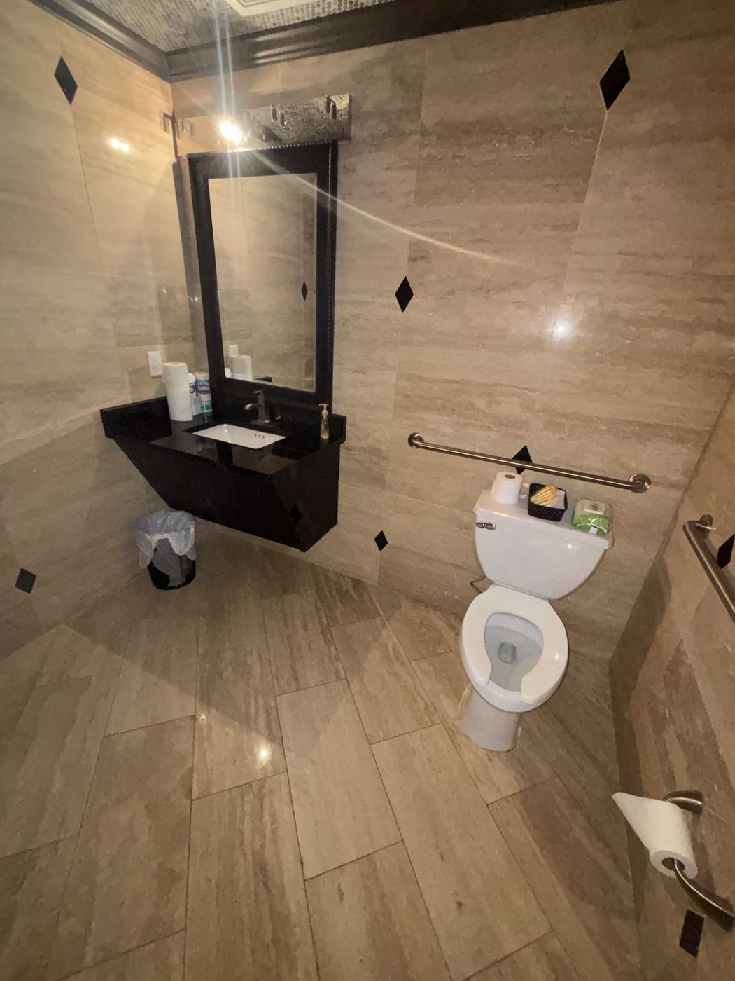 Spotless commercial restroom with polished stone tile and restocked supplies